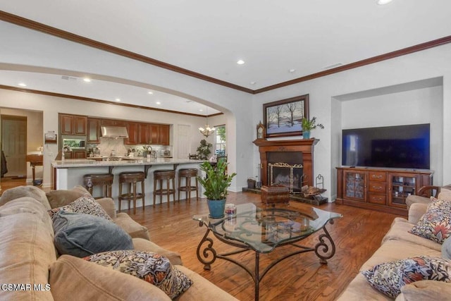 living room featuring a notable chandelier, ornamental molding, and light hardwood / wood-style floors