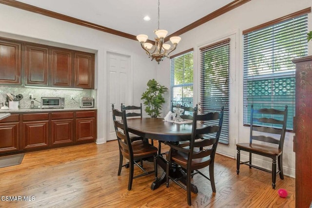 dining area featuring a notable chandelier, ornamental molding, and light wood-type flooring