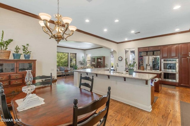 dining space featuring sink, crown molding, light hardwood / wood-style floors, and a chandelier