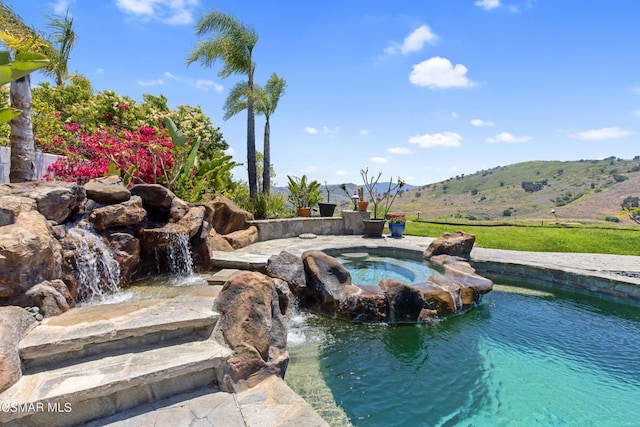 view of pool with an in ground hot tub, pool water feature, and a mountain view