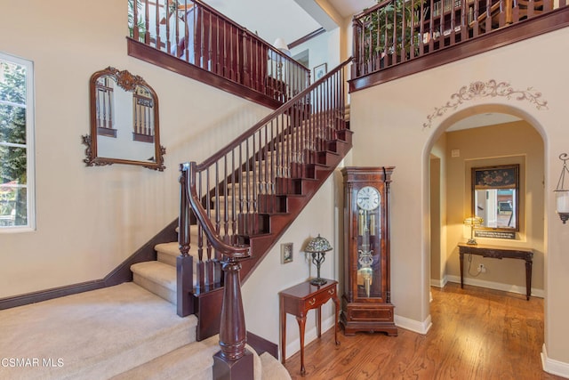 stairway with hardwood / wood-style floors and a towering ceiling