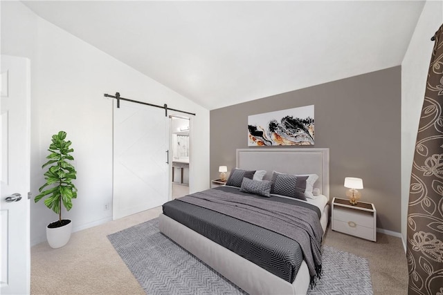 carpeted bedroom with connected bathroom, a barn door, and vaulted ceiling