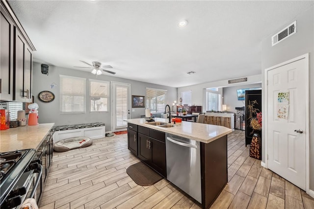 kitchen featuring dark brown cabinetry, stainless steel appliances, sink, and a center island with sink