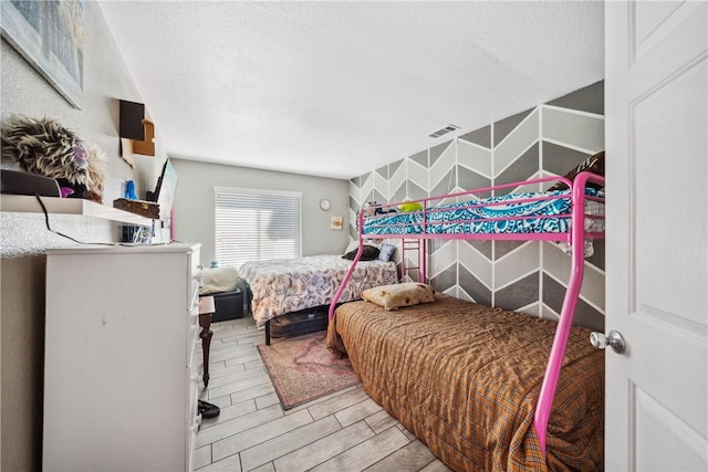 bedroom with visible vents, a textured ceiling, and wood finish floors