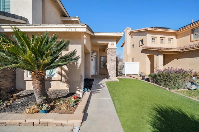 doorway to property featuring stucco siding, fence, and a yard