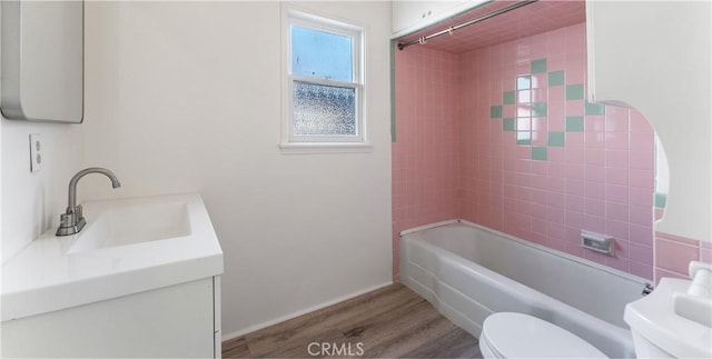 full bathroom featuring vanity, hardwood / wood-style floors, tiled shower / bath combo, and toilet