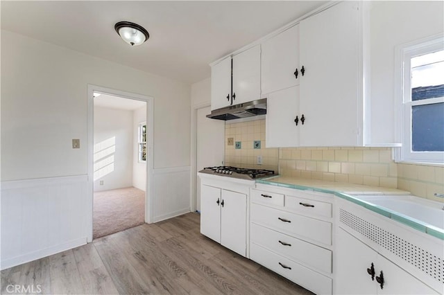 kitchen featuring white cabinetry, light hardwood / wood-style flooring, tasteful backsplash, and plenty of natural light