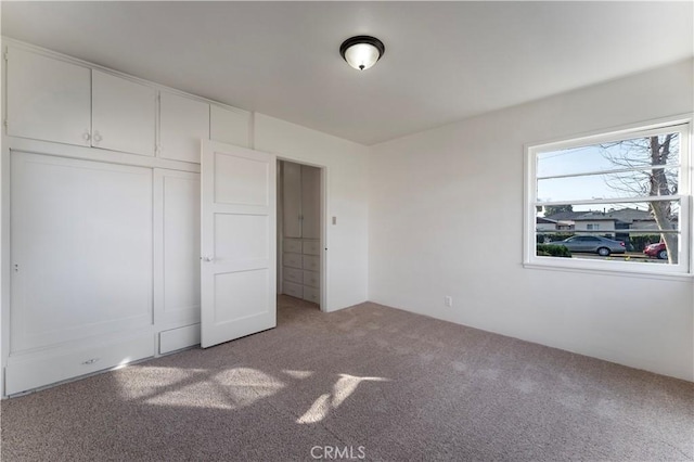 unfurnished bedroom featuring light colored carpet and a closet