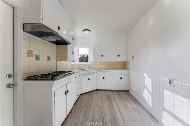 kitchen featuring sink, white cabinets, decorative backsplash, stainless steel gas cooktop, and light wood-type flooring