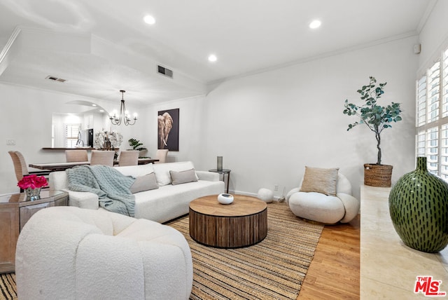 living room featuring crown molding, an inviting chandelier, and light wood-type flooring