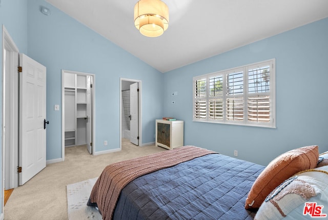 bedroom featuring light carpet, a spacious closet, and vaulted ceiling