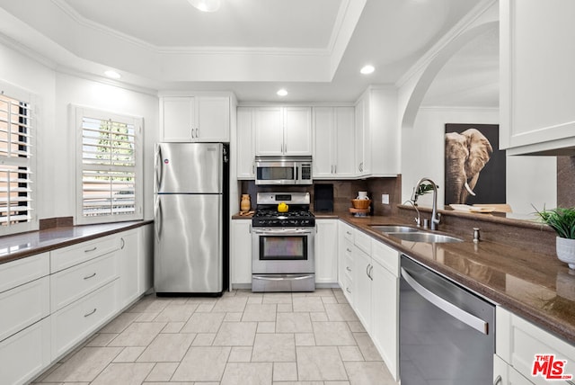 kitchen featuring stainless steel appliances, a raised ceiling, sink, and white cabinetry