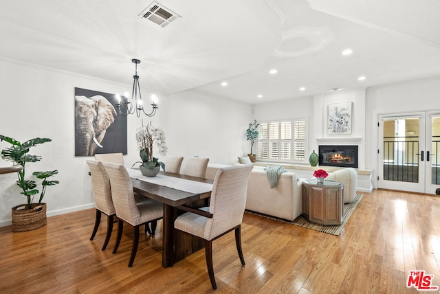 dining space featuring a notable chandelier, light hardwood / wood-style floors, and french doors