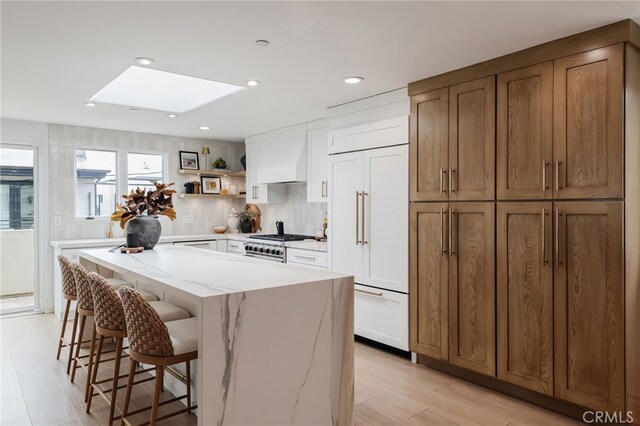 kitchen with high end appliances, white cabinetry, a skylight, and a center island