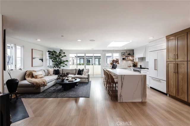 kitchen with paneled built in fridge, a kitchen island, open floor plan, a kitchen bar, and white cabinetry