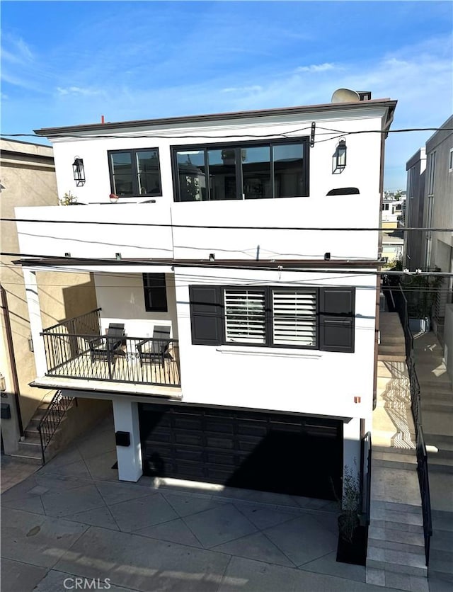 back of house with stairway, a patio, a balcony, and stucco siding