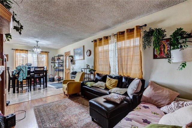 living room featuring an inviting chandelier, hardwood / wood-style floors, and a textured ceiling