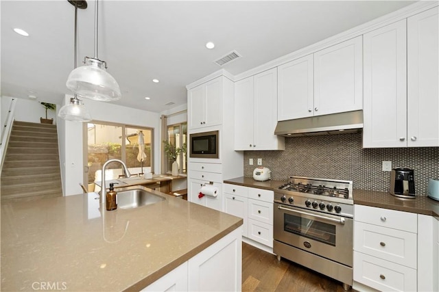 kitchen with sink, high end range, decorative light fixtures, black microwave, and white cabinets