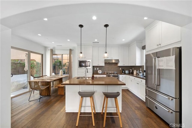 kitchen with sink, a center island with sink, appliances with stainless steel finishes, pendant lighting, and white cabinets