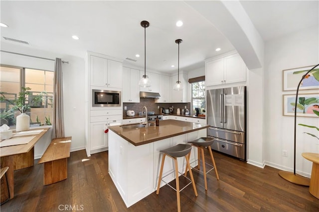 kitchen featuring sink, white cabinetry, high quality fridge, a center island with sink, and built in microwave