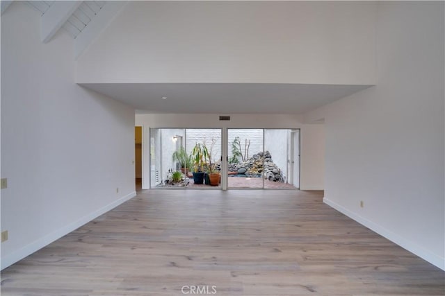 unfurnished living room featuring high vaulted ceiling and light wood-type flooring