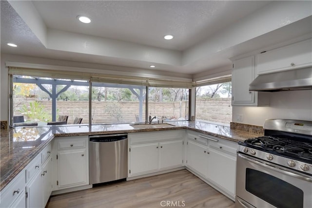 kitchen with sink, white cabinetry, stainless steel appliances, light hardwood / wood-style floors, and dark stone counters