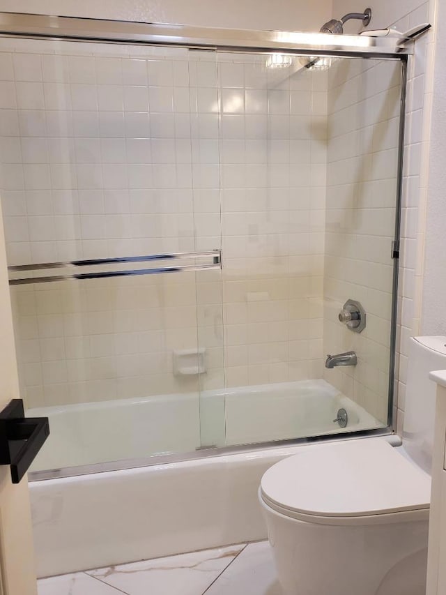 bathroom featuring bath / shower combo with glass door and toilet