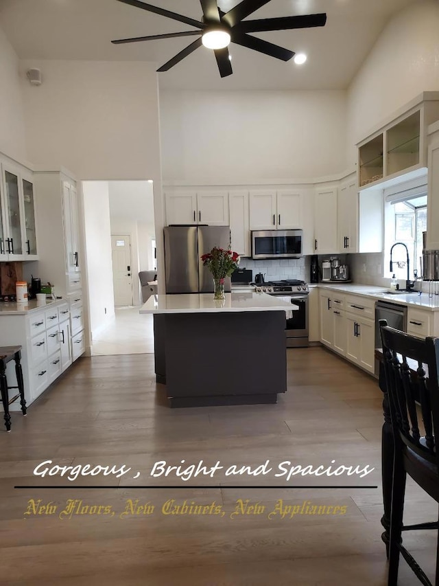 kitchen with stainless steel appliances, sink, a high ceiling, and white cabinets