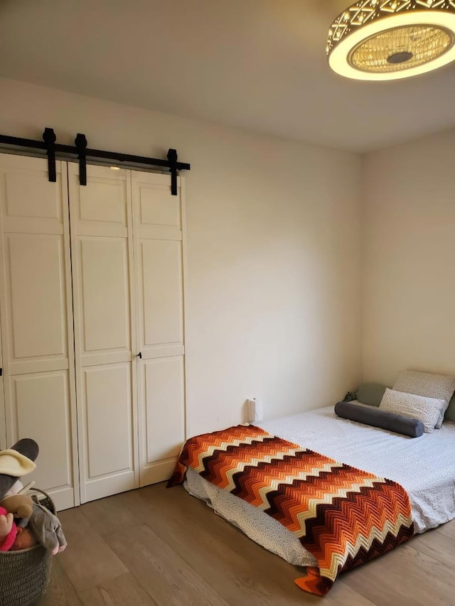 bedroom featuring wood-type flooring and a barn door