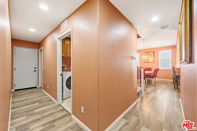 hallway with washer / clothes dryer and light wood-type flooring