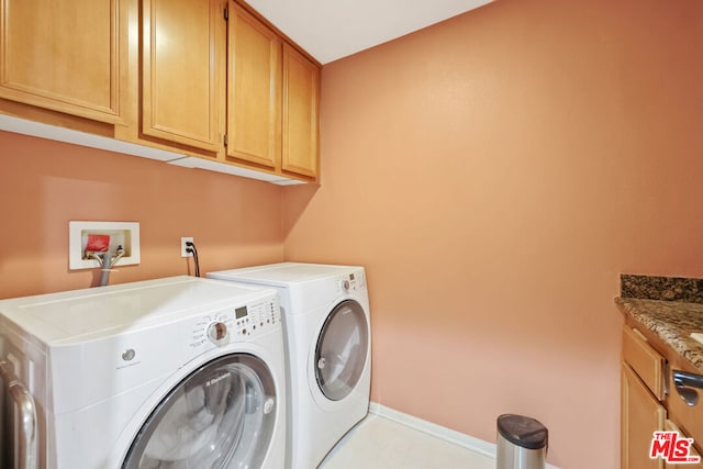 clothes washing area featuring washer and clothes dryer and cabinets