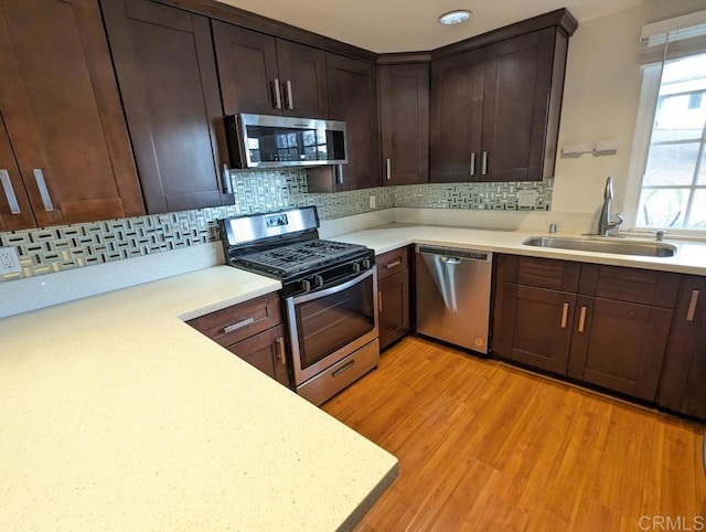 kitchen with stainless steel appliances, sink, backsplash, and light hardwood / wood-style floors