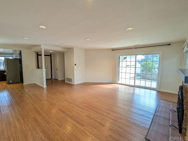 unfurnished living room with decorative columns and light wood-type flooring