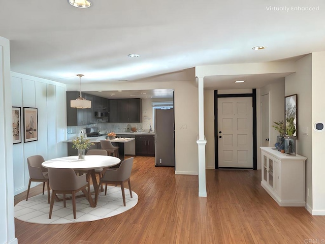 dining room with ornate columns and light hardwood / wood-style flooring