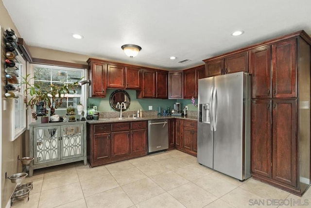 kitchen with stainless steel appliances, stone countertops, sink, and light tile patterned flooring