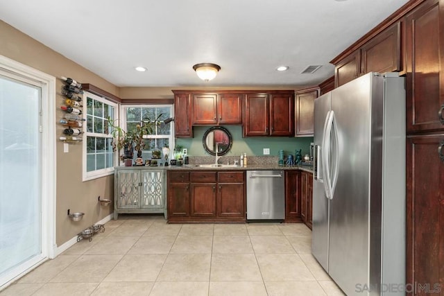 kitchen with stainless steel appliances, sink, dark stone counters, and light tile patterned floors