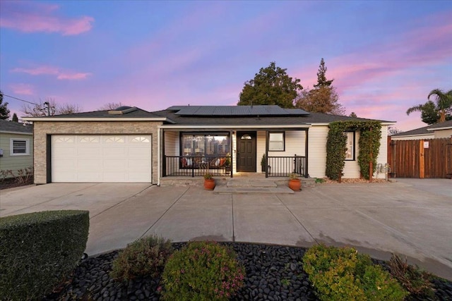 single story home featuring a garage, covered porch, and solar panels