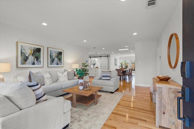 living room with a barn door and light hardwood / wood-style floors