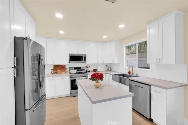 kitchen featuring sink, tasteful backsplash, appliances with stainless steel finishes, a kitchen island, and white cabinets