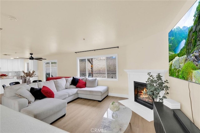 living room featuring ceiling fan, plenty of natural light, and light hardwood / wood-style flooring