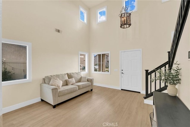 living room with an inviting chandelier, a high ceiling, and light wood-type flooring