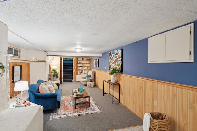 living room with carpet, wooden walls, a textured ceiling, and built in shelves