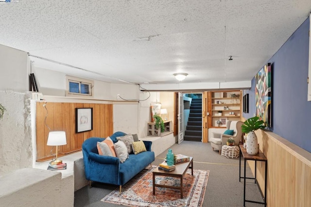 carpeted living room with wooden walls and a textured ceiling