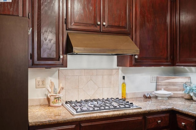 kitchen with light stone counters, stainless steel gas cooktop, custom range hood, and backsplash