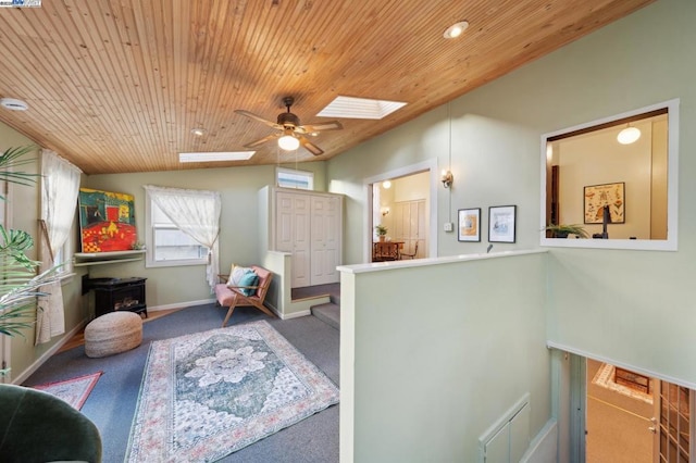 living area with lofted ceiling with skylight, carpet floors, wooden ceiling, and ceiling fan