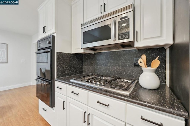 kitchen with white cabinetry, appliances with stainless steel finishes, light wood-type flooring, and backsplash