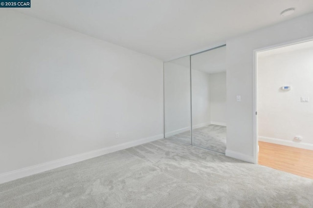 unfurnished bedroom with light colored carpet and a closet