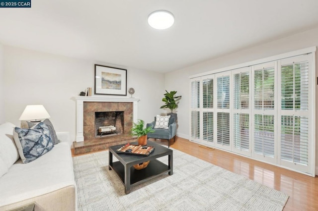 living room with a tiled fireplace and hardwood / wood-style flooring