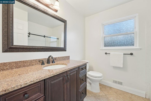 bathroom featuring tile patterned flooring, vanity, a shower with door, and toilet