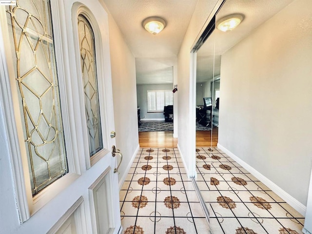 foyer entrance with a textured ceiling and light tile patterned floors